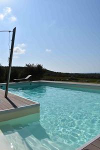 a large blue swimming pool with a wooden deck at CASA MARE e TRAMONTO in Monte Marzeddu