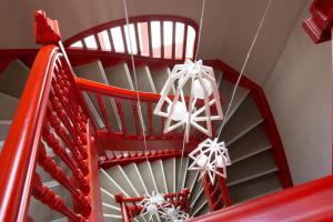 Un escalier rouge avec des archets de christmas dessus dans l'établissement Hotel D - Strasbourg, à Strasbourg