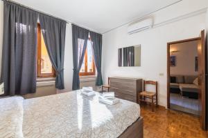 a bedroom with a bed and a chair and windows at Firenze Rentals Ponte Vecchio Flat in Florence