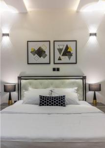 ein Schlafzimmer mit einem weißen Bett mit drei Bildern an der Wand in der Unterkunft Oslo Apartment in Abuja