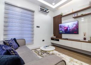 a living room with a couch and a flat screen tv at Oslo Apartment in Abuja