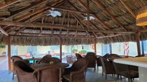 a restaurant with chairs and tables and a thatched ceiling at Najhomi Beach in Santa Marta
