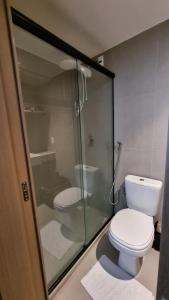 a bathroom with a toilet and a glass shower at Flat Bauten Cabo branco AP301 in João Pessoa