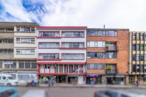 a tall brick building with a red and white facade at Hotel Lourdes la 62 in Bogotá