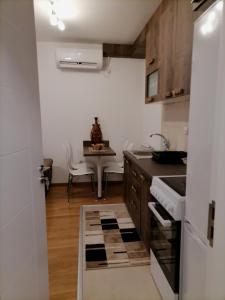 uma pequena cozinha com um lavatório e uma mesa em APARTMAN ANA em Niš