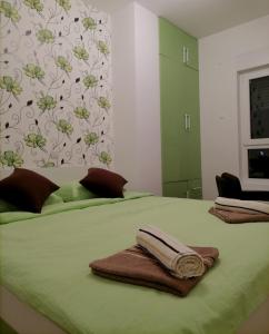 Una cama con sábanas verdes y toallas. en APARTMAN ANA, en Niš