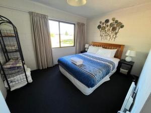 een slaapkamer met een bed met een blauwe deken en een raam bij Opera House Beside the Lake in Lake Tekapo