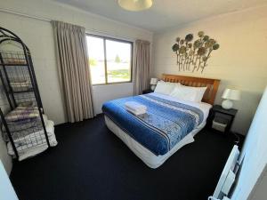 a bedroom with a bed with a blue blanket and a window at Opera House Beside the Lake in Lake Tekapo