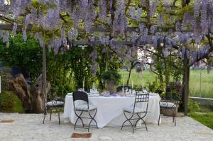 una mesa con glicinas púrpuras colgando de una pérgola en Ca'Bevilacqua Bed&Breakfast, en Bertinoro
