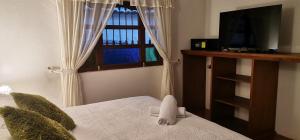 a bedroom with a bed with a window and a tv at Hotel Villa del Angel in Villa de Leyva