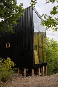a black house with a window on a wooden platform at Andrómeda Lodge in Las Trancas