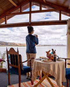 Eine Frau, die aus einem Fenster an einen Tisch schaut. in der Unterkunft Luz del Titicaca Lodge in Puno