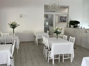 a dining room with white tables and white chairs at Garnì Stella Marina in Cervia