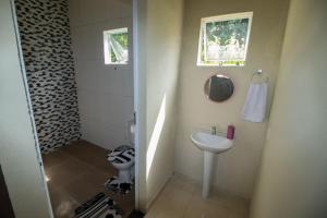 uma pequena casa de banho com lavatório e WC em Pousada Recanto do Galo em Santa Cruz Cabrália