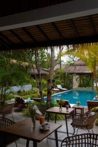 patio ze stołami i krzesłami oraz basenem w obiekcie Amaya Boutique Resort w mieście Baan Srithanu