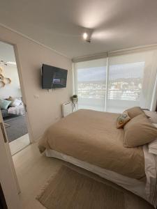 a bedroom with a large bed and a large window at Departamento de lujo Estacionamiento privado y cocina integral in Viña del Mar