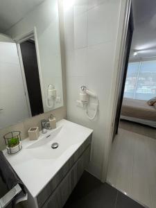 a white bathroom with a sink and a mirror at Departamento de lujo Estacionamiento privado y cocina integral in Viña del Mar