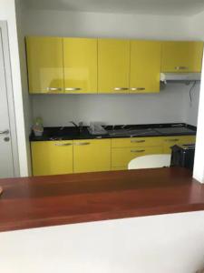 a kitchen with yellow cabinets and a wooden counter top at Meublé de standing au coeur des commodités in Schœlcher