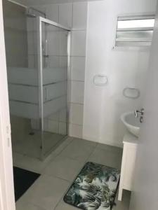 a white bathroom with a shower and a sink at Meublé de standing au coeur des commodités in Schœlcher