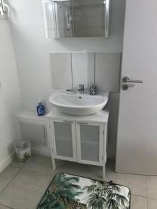 a white bathroom with a sink and a mirror at Meublé de standing au coeur des commodités in Schœlcher