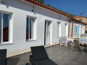 a white house with a patio with chairs and a table at Casa Laryssiou in Gythio