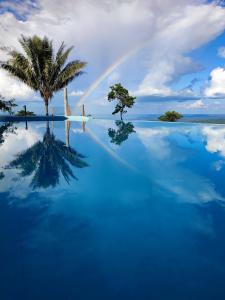 einen Regenbogen über einem Pool mit einer Palme in der Unterkunft Finca Heimatlos in Puyo