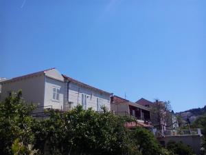 un edificio blanco con árboles en el primer plano en Apartment Ljilja, en Dubrovnik