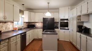 a kitchen with white cabinets and a black refrigerator at Luxurious Pool Cottage in Kingsville