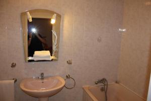 une personne prenant une photo d'une salle de bains avec lavabo et baignoire dans l'établissement Hotel Restaurant La Camargue, à Salin-de-Giraud