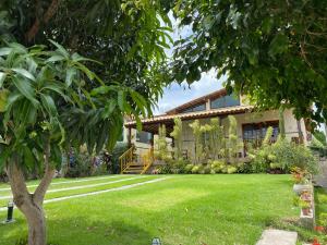 una casa con un patio verde con un árbol en Gravata em Condomínio LINDO - Casa com 200m com 4 QTS e 5 WC, en Gravatá