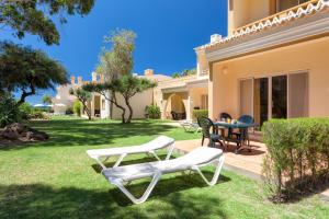 a yard with two white chairs and a table at Pestana Palm Gardens in Carvoeiro