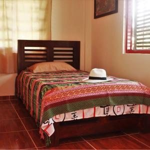 Una cama con un sombrero encima. en Alojamiento Rural Café Yarumo, en Buenavista