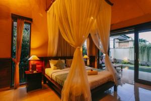 a bedroom with a bed with a mosquito net at Puri Arta Villa in Ubud