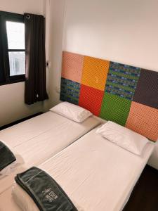 two beds in a room with a colorful wall at Eden Hotel Bangsean in Ban Laem Thaen