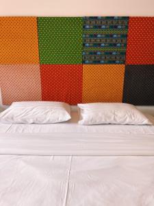 a bed with two pillows in front of a colorful wall at Eden Hotel Bangsean in Ban Laem Thaen