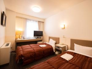 ein Hotelzimmer mit 2 Betten und einem TV in der Unterkunft Hotel Iidaya in Matsumoto