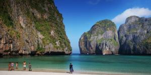 a group of people standing on a beach with limestone cliffs at Phi Phi Relax Beach Resort in Phi Phi Islands