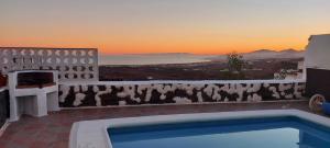 a pool with a view of the ocean at sunset at ALOELUXVILLA COM (II) in Tías