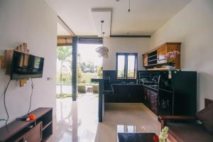 a kitchen with black appliances and a tv in a room at Puri Arta Villa in Ubud