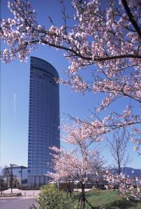 a building with a cherry tree in front of it at Lake Biwa Otsu Prince Hotel in Otsu