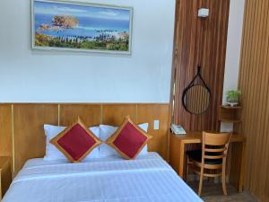 ein Schlafzimmer mit einem Bett und einem Schreibtisch mit einem Stuhl in der Unterkunft King Hotel in Quy Nhon