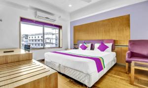 a bedroom with a large bed and a purple chair at Medora Hotel in Kozhikode