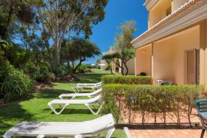 a row of white lounge chairs in a yard at Pestana Palm Gardens in Carvoeiro