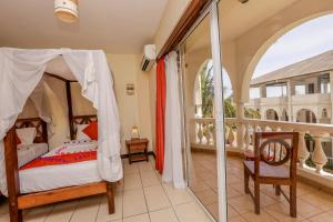 a bedroom with a canopy bed and a balcony at CityBlue Creekside Hotel & Suites in Mombasa