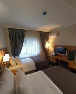 een hotelkamer met twee bedden, een bureau en een televisie bij AK LİFE HOTEL&SUIT in Ankara