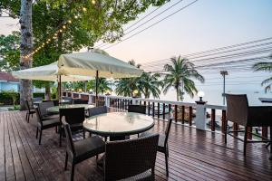 a patio with tables and chairs and an umbrella at RimLay Beachfront Pool Villa in Sattahip