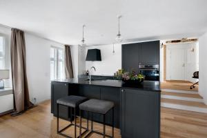 a kitchen with black cabinets and a kitchen island with stools at Sanders Regent - Chic Three-Bedroom Apartment Near Central Square in Copenhagen +28 photos