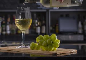 a glass of white wine next to a bunch of grapes at Holiday Inn & Suites Silicon Valley - Milpitas by IHG in Milpitas