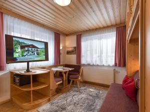 a living room with a television and a table with a chair at Appartementhaus Mühlberger in Ellmau