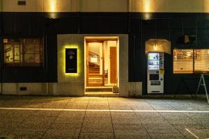 een deur naar een gebouw 's nachts met een bord erop bij SINGAI CABIN in Onomichi